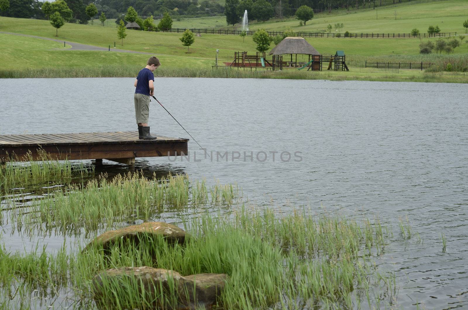 Boy bass fishing on dam or lake pier