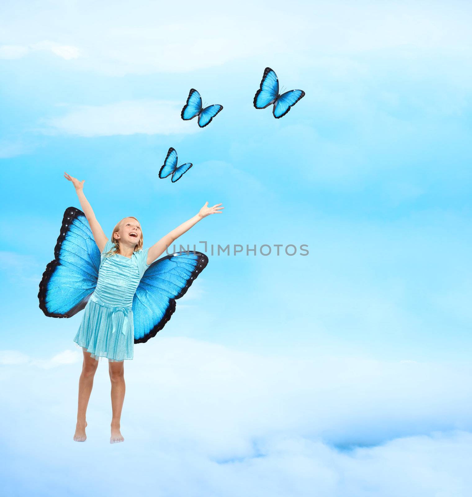 Happy Young Girl in Blue Dress with Arms in the Air Releasing Butterflies 