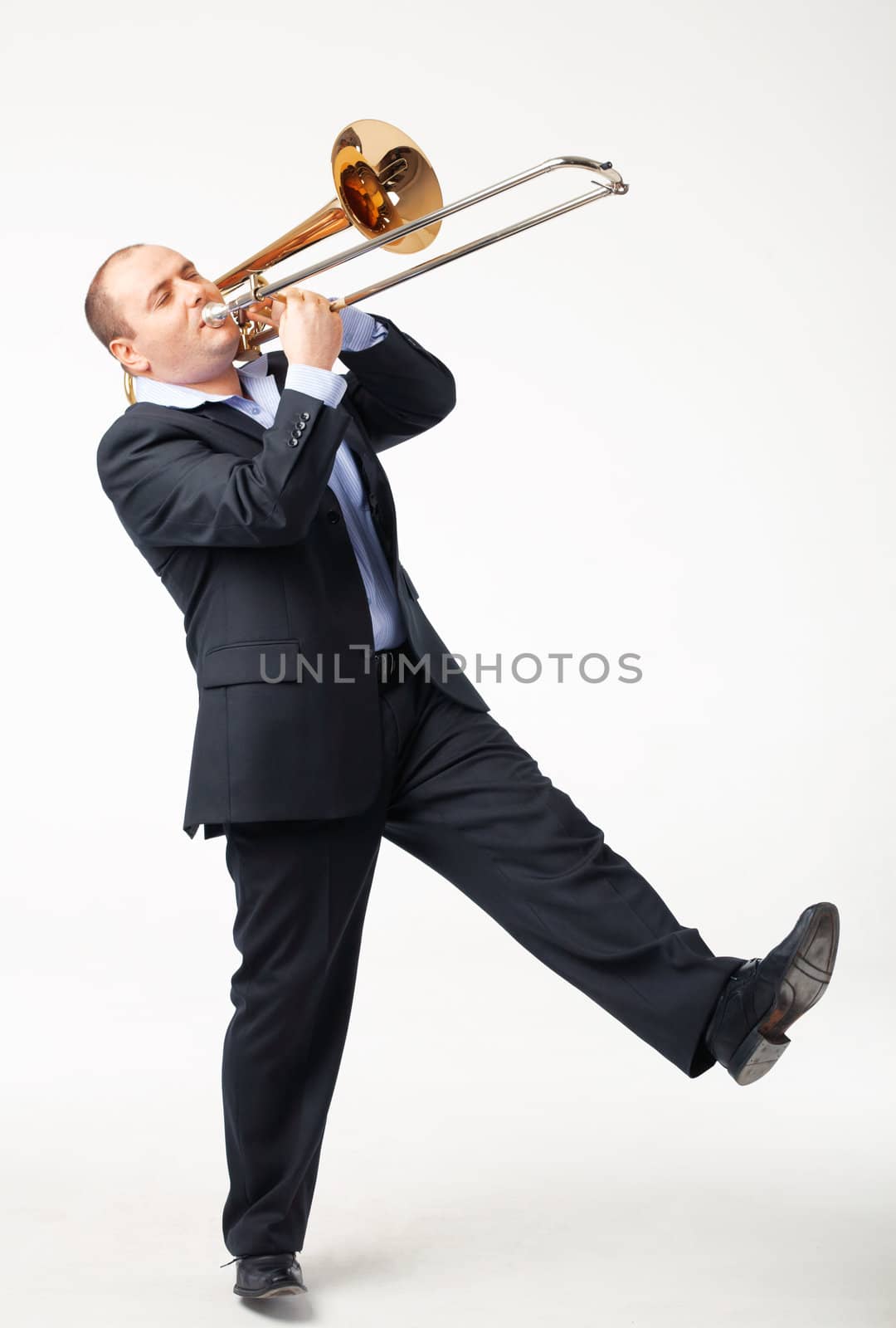 Portrait of a young man playing his trombone on white