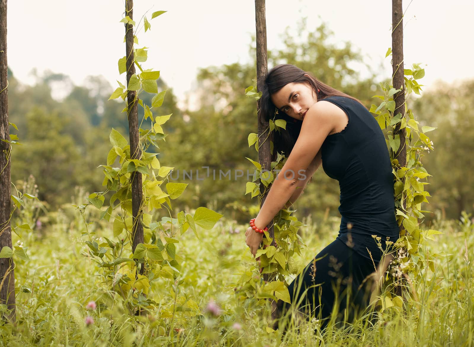 Portrait of beautiful model in black on nature background, posing.