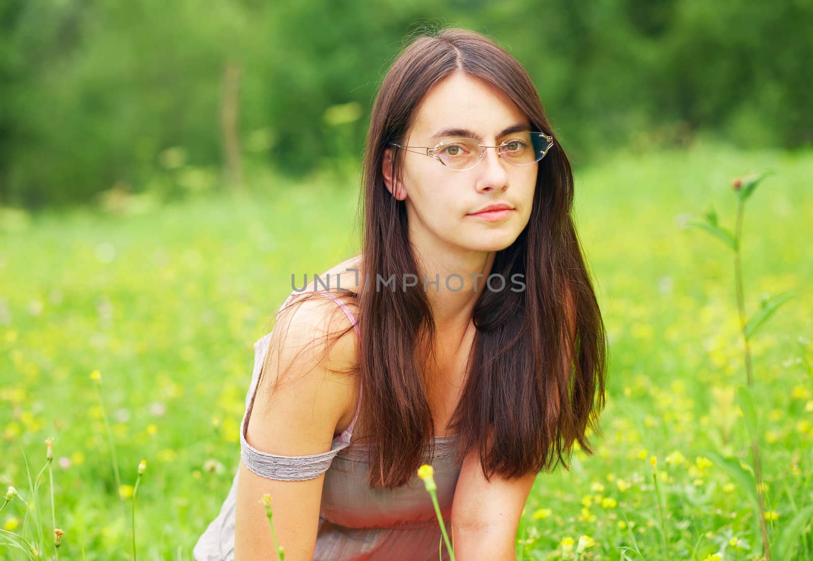 Portrait of a woman. She is sitting in a green meadow