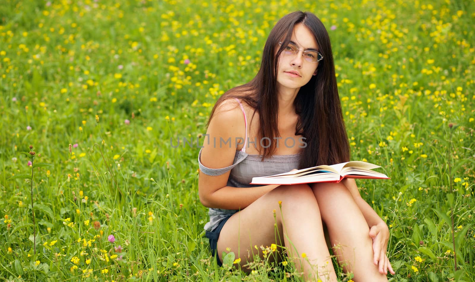 Young  female with a book  on a green meadow