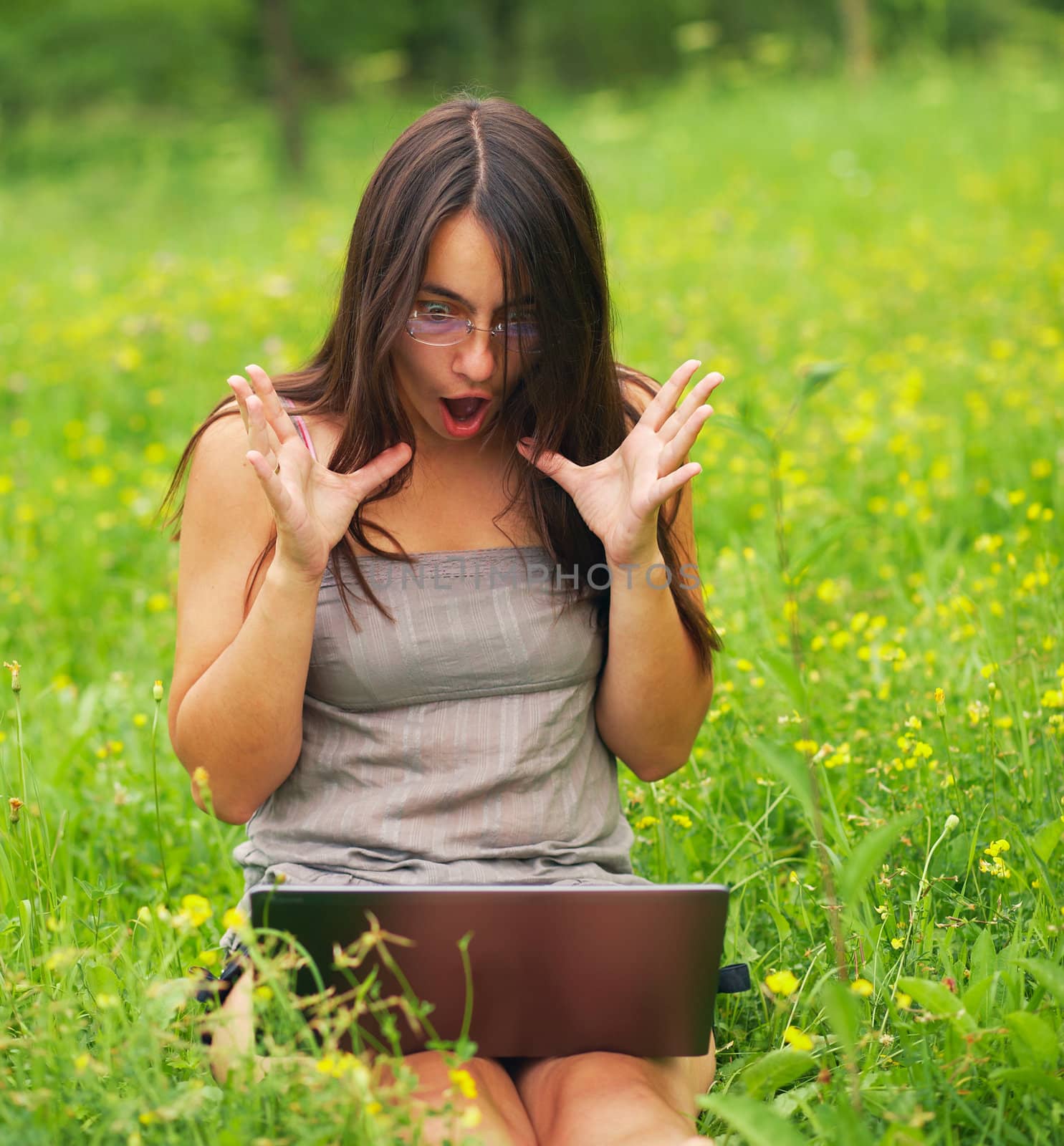 Shocked Young woman using her laptop outdoors.