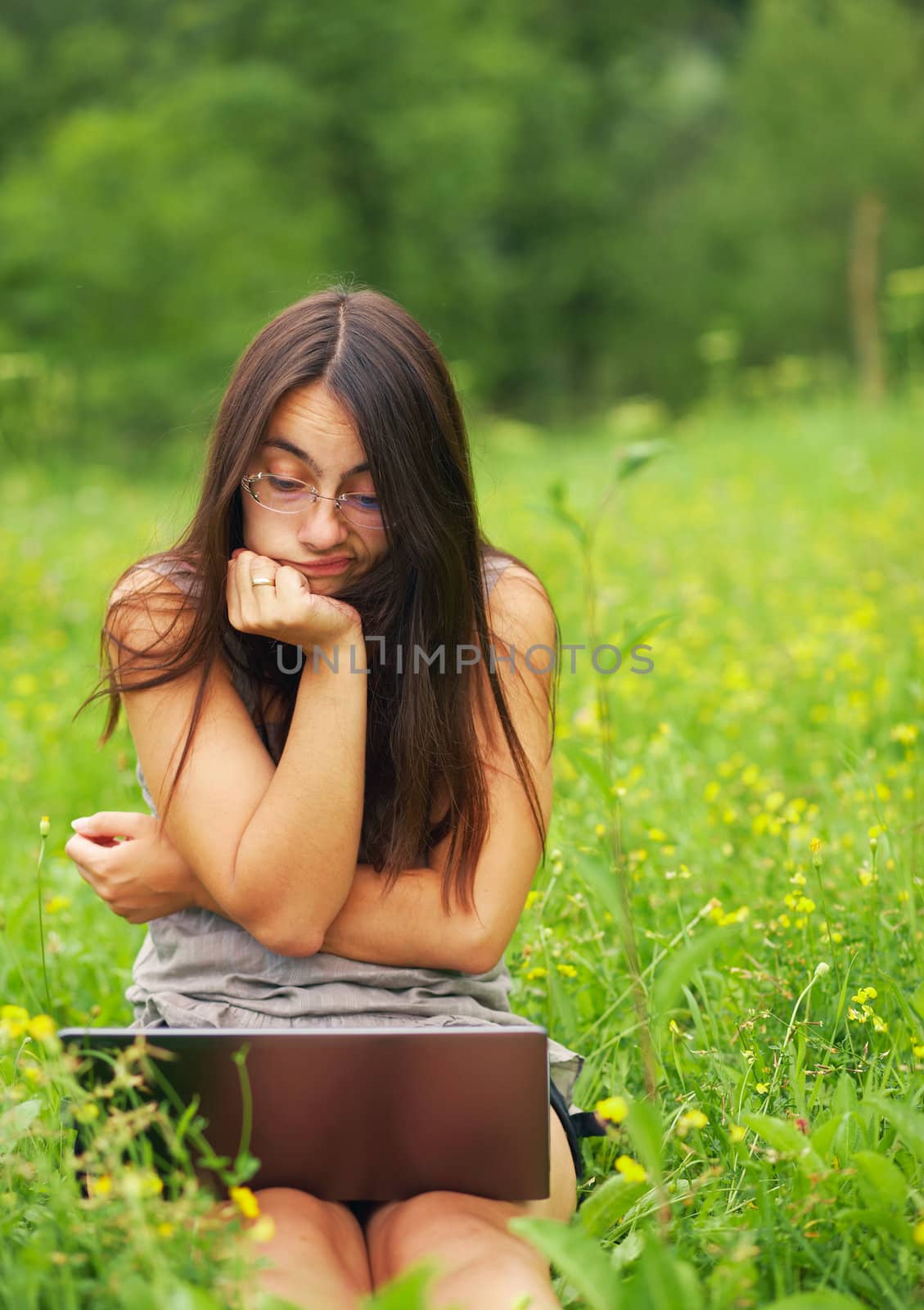 Worried young woman using her laptop outdoors.