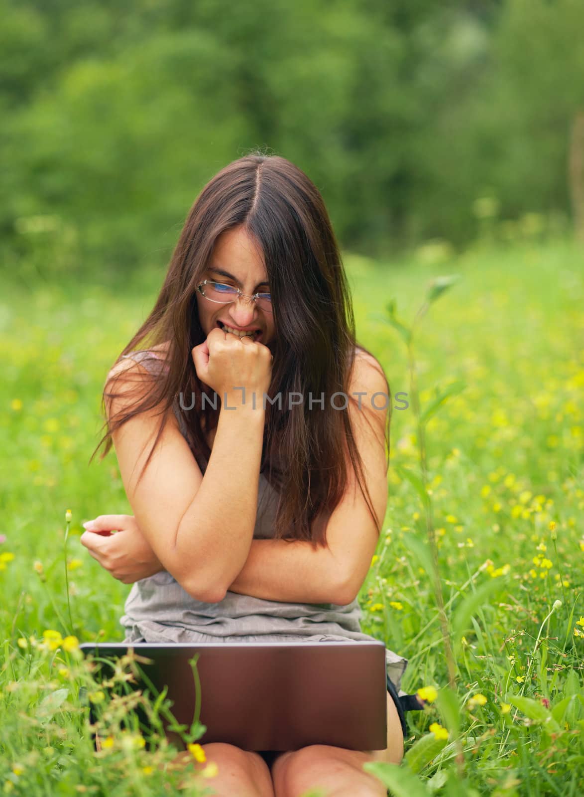 Angry young woman using her laptop outdoors.