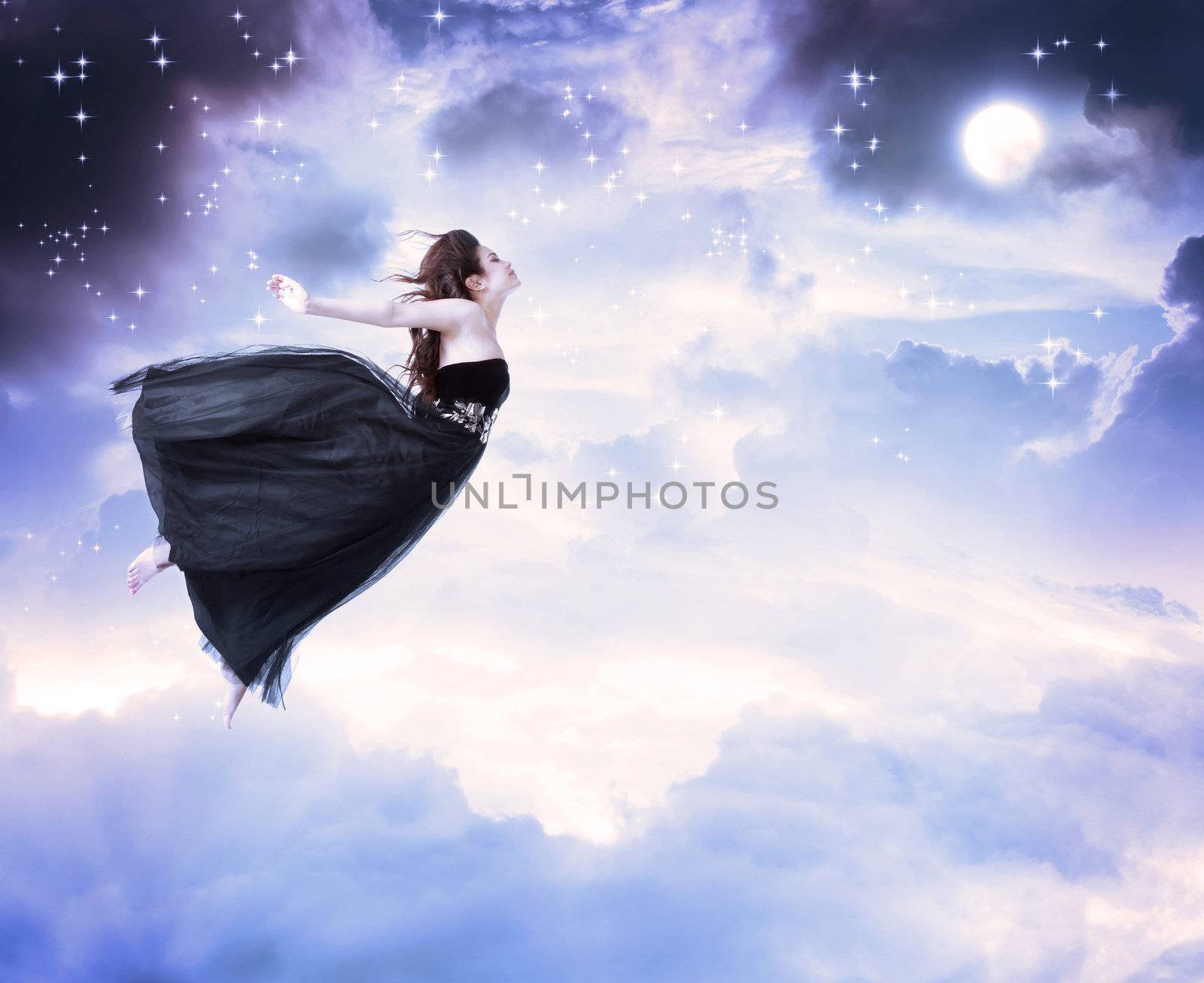 Girl in beautiful black dress jumping in the moonlight sky (serenity)