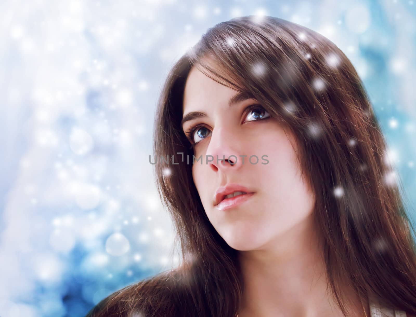Beaurtiful young woman looking upward with shinning blue background