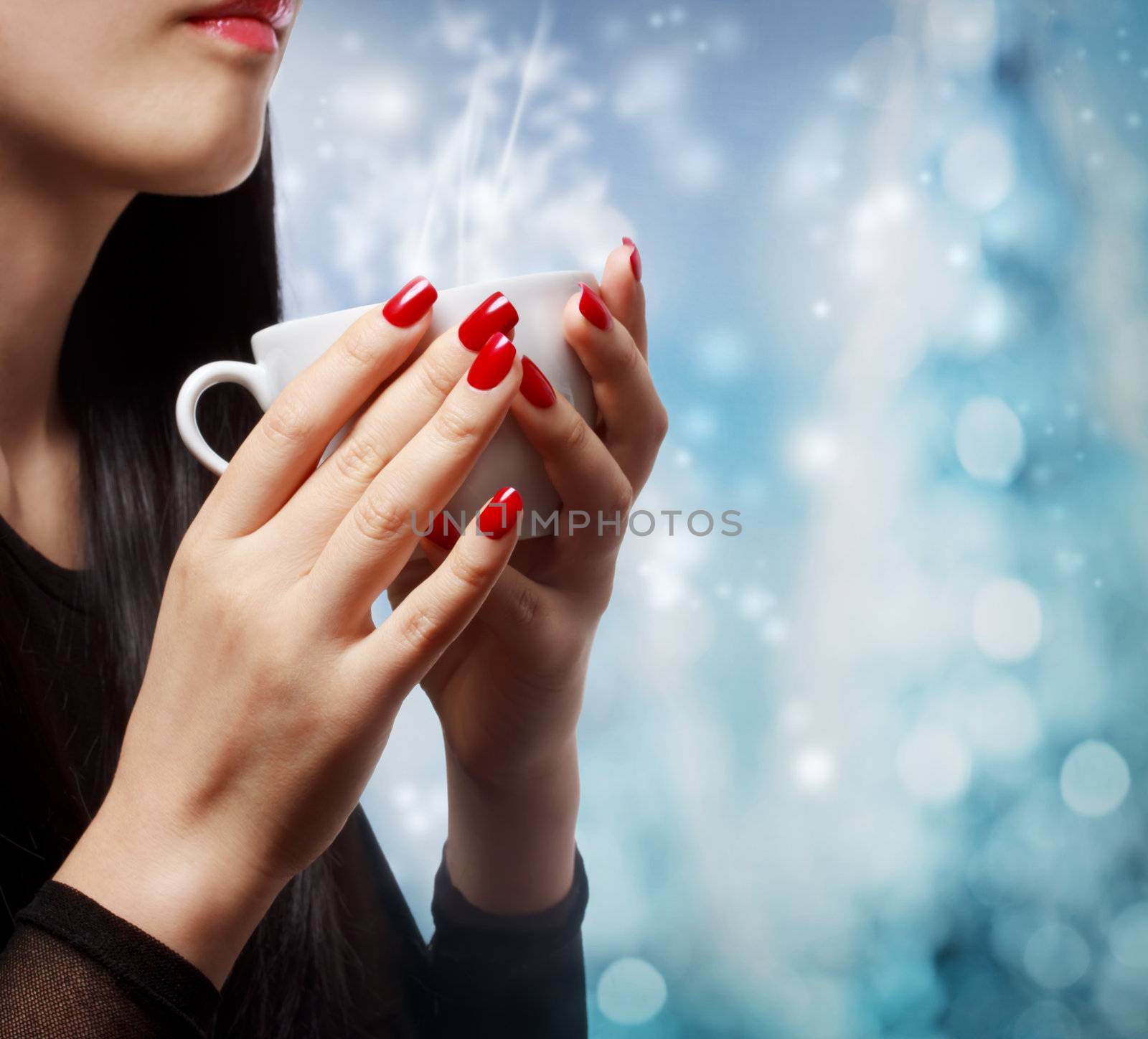 Beautiful woman holding a hot beverage on blue bokeh background