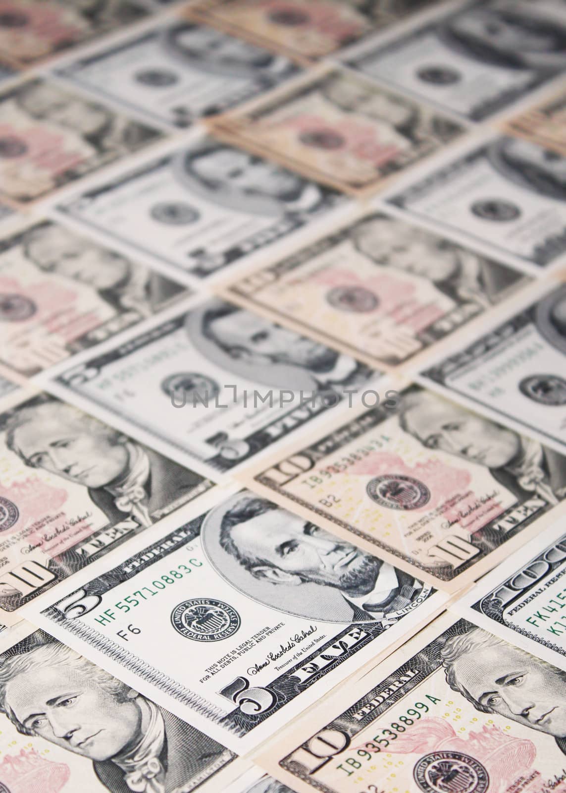 Background of five, ten and a hundred dollar banknotes neatly arranged, with shallow depth of field.