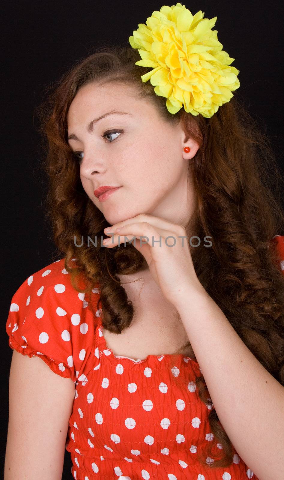 Portrait of a beautiful girl with a flower in her hair on a black background