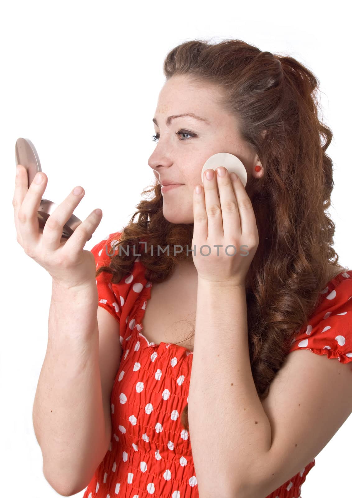 Girl putting facial powder on her face, white background.