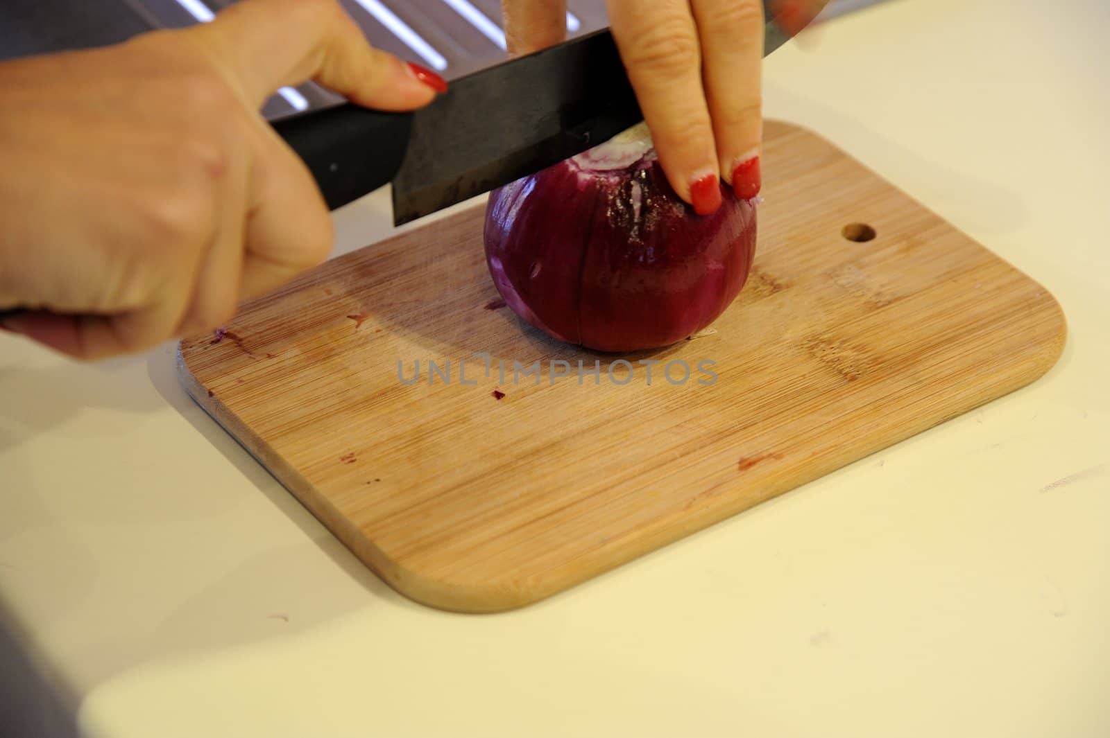 The hands cutting onions on a chopping board by mizio1970