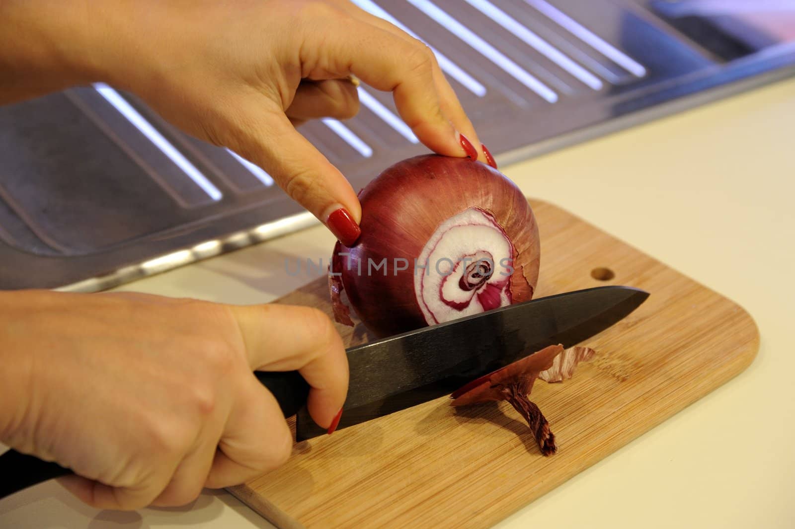 The hands cutting onions on a chopping board by mizio1970