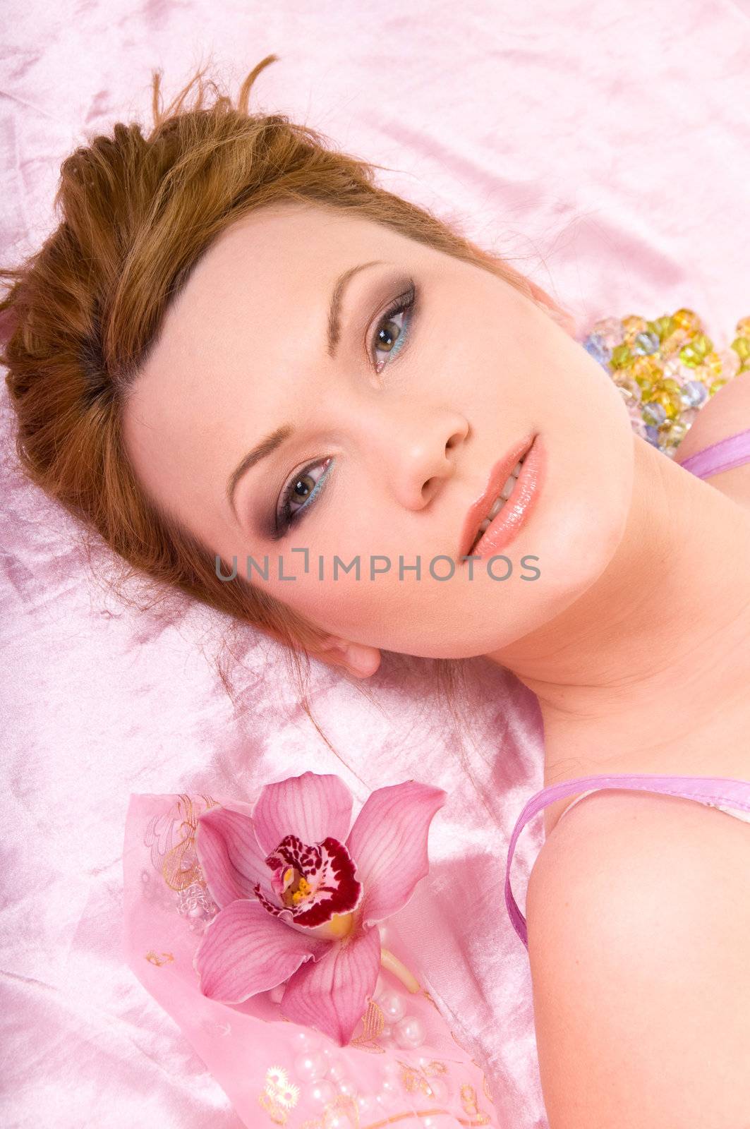 Beautiful woman with nice make-up and orchid flower on pink backgroumd