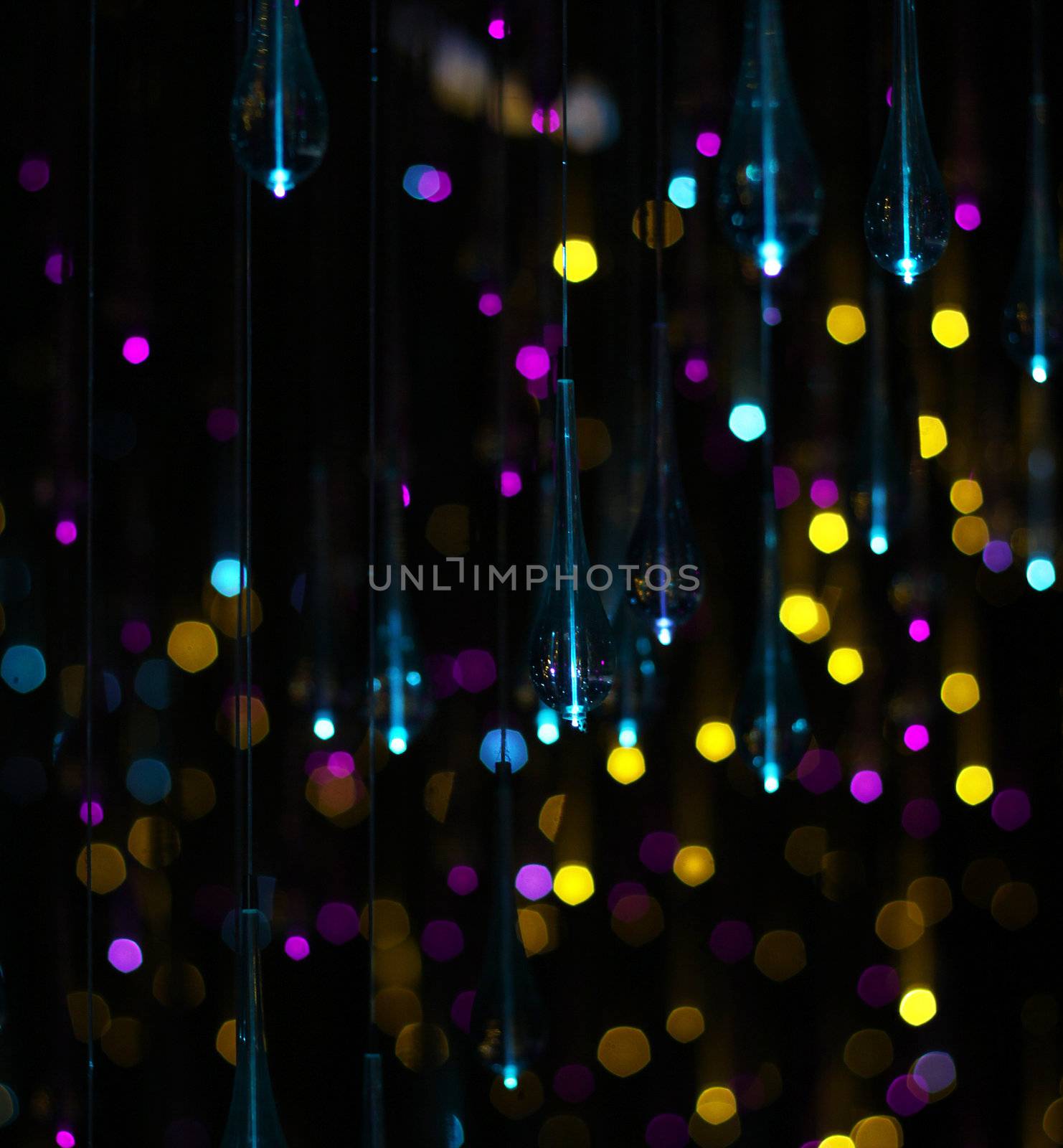 hanging glass drops with Pink, yellow, blue glitter bokeh on black background