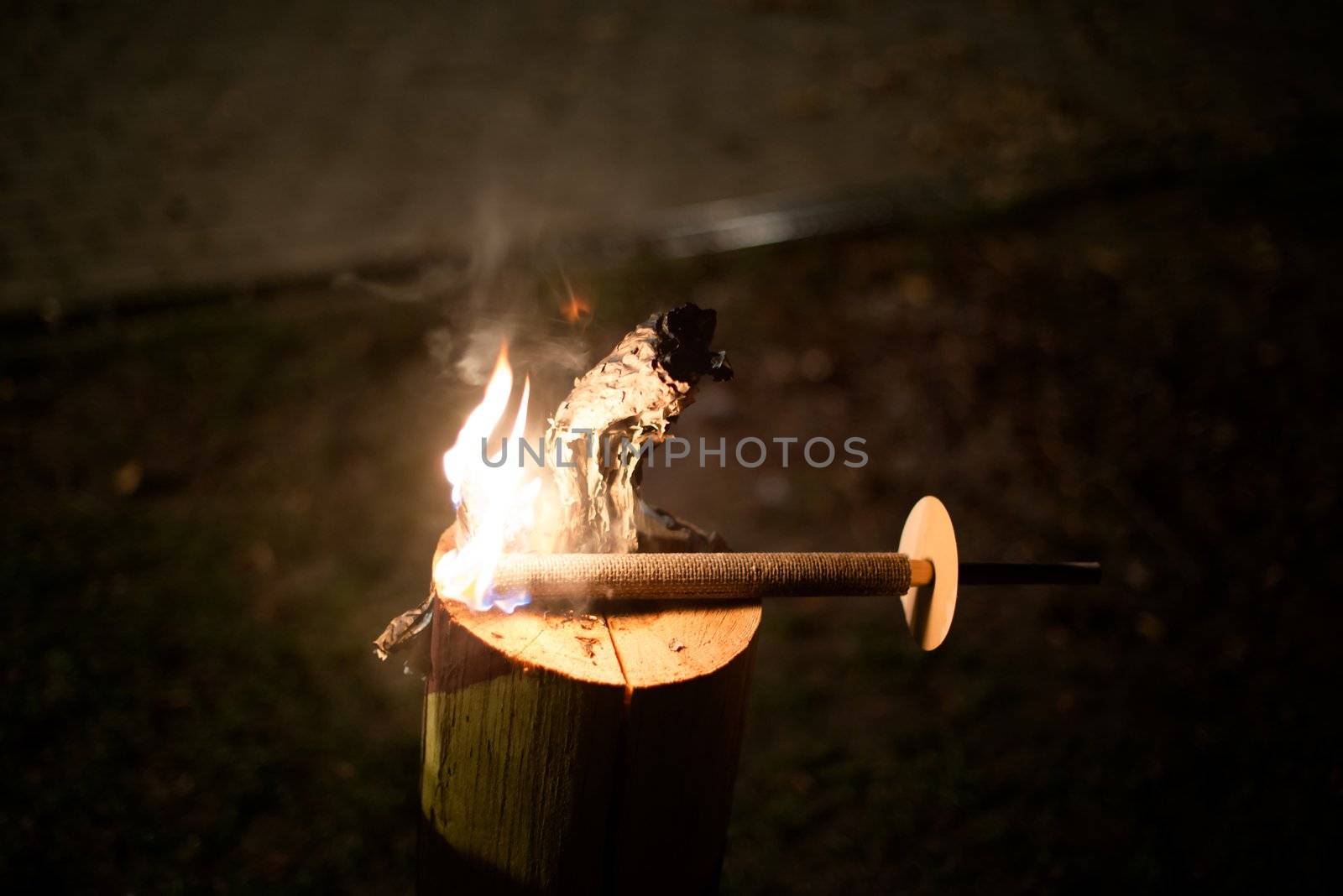 Torch burning on a wooden stump at night