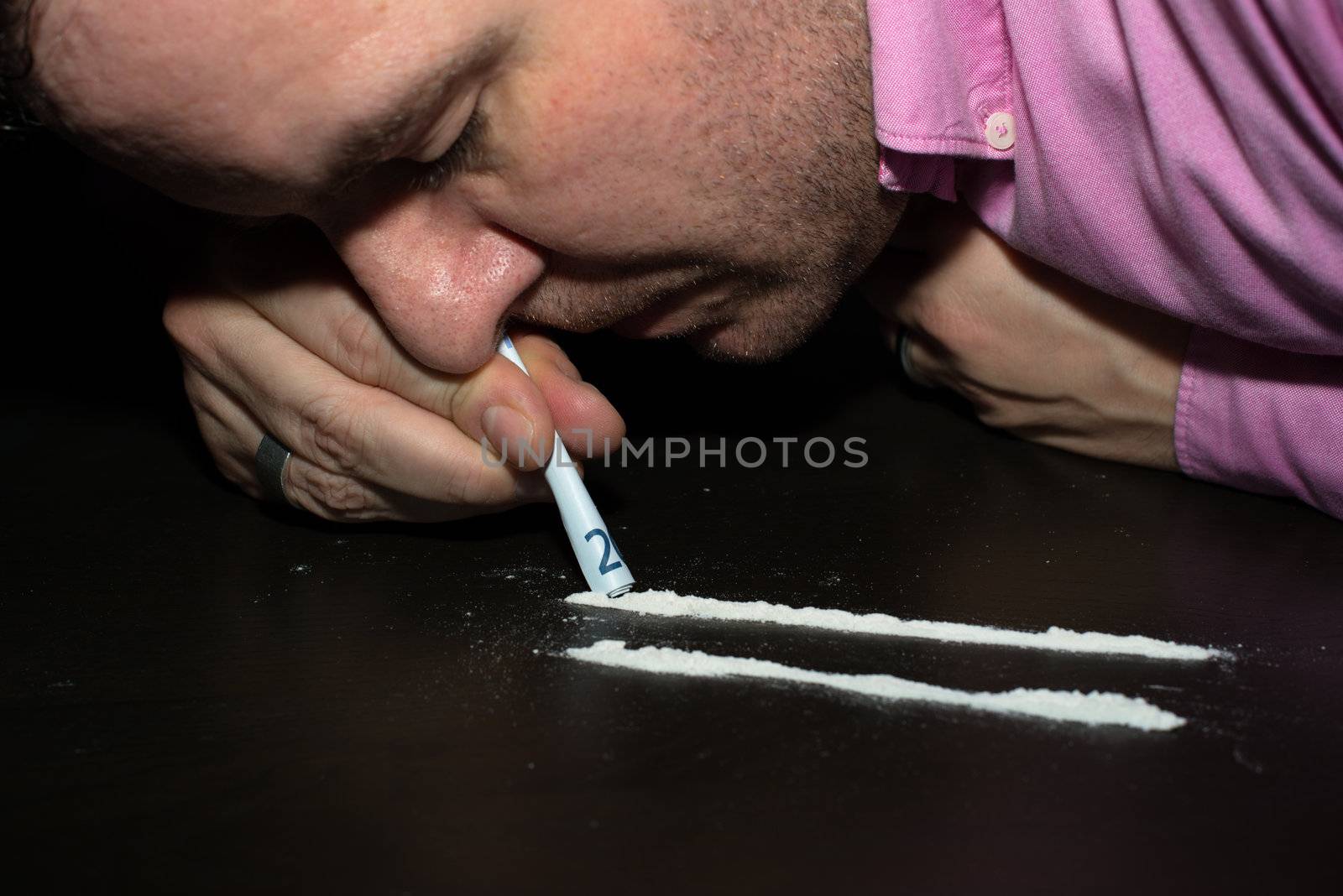 Drug Abuse: Young man sniffing cocaine using a EURO note
