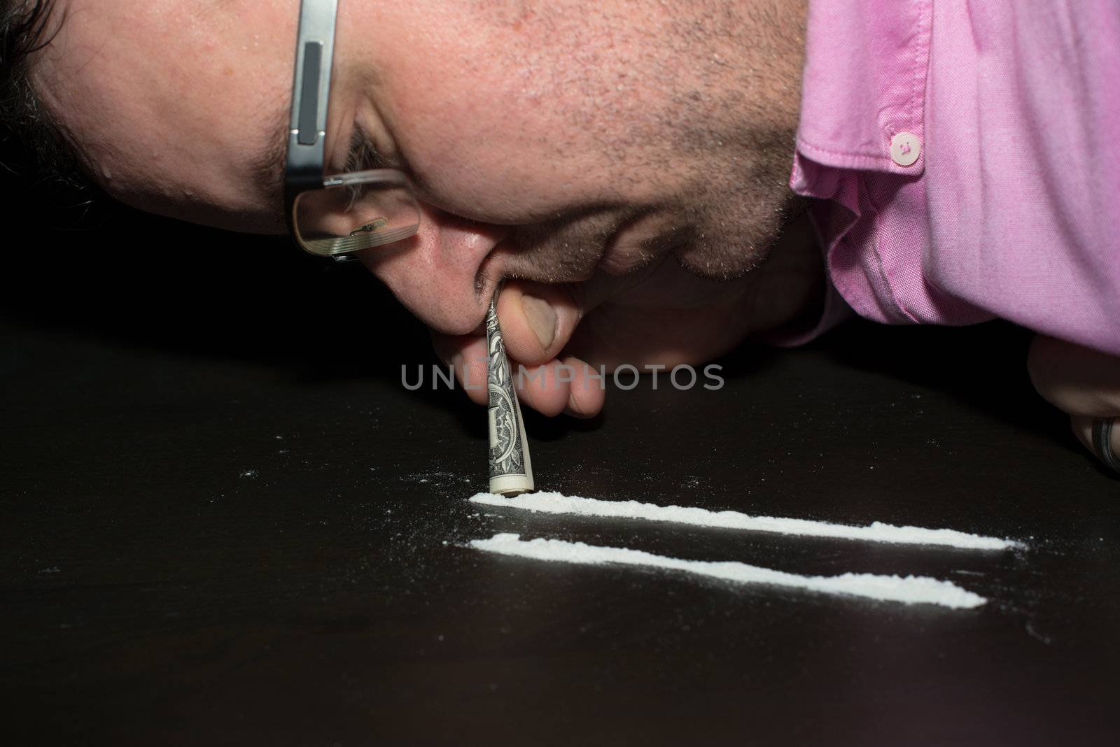 Drug Abuse: Young man sniffing cocaine using a Dollar note