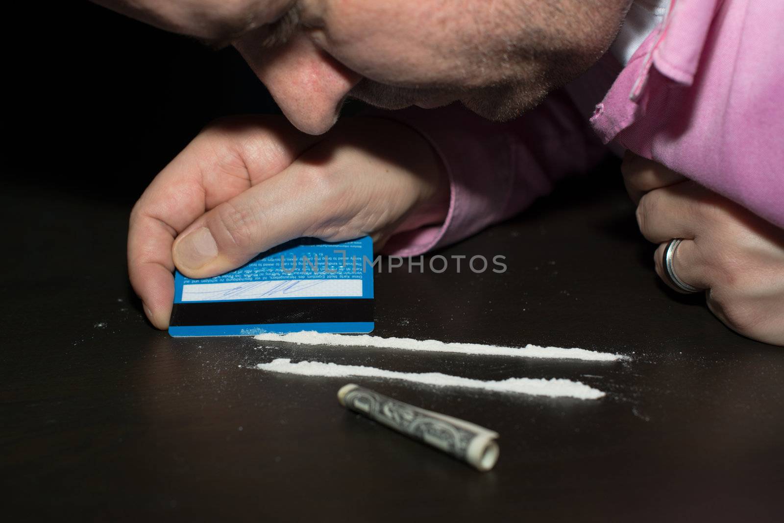 Drug abuse: Young man preparing cocaine for sniffing using a credit card.