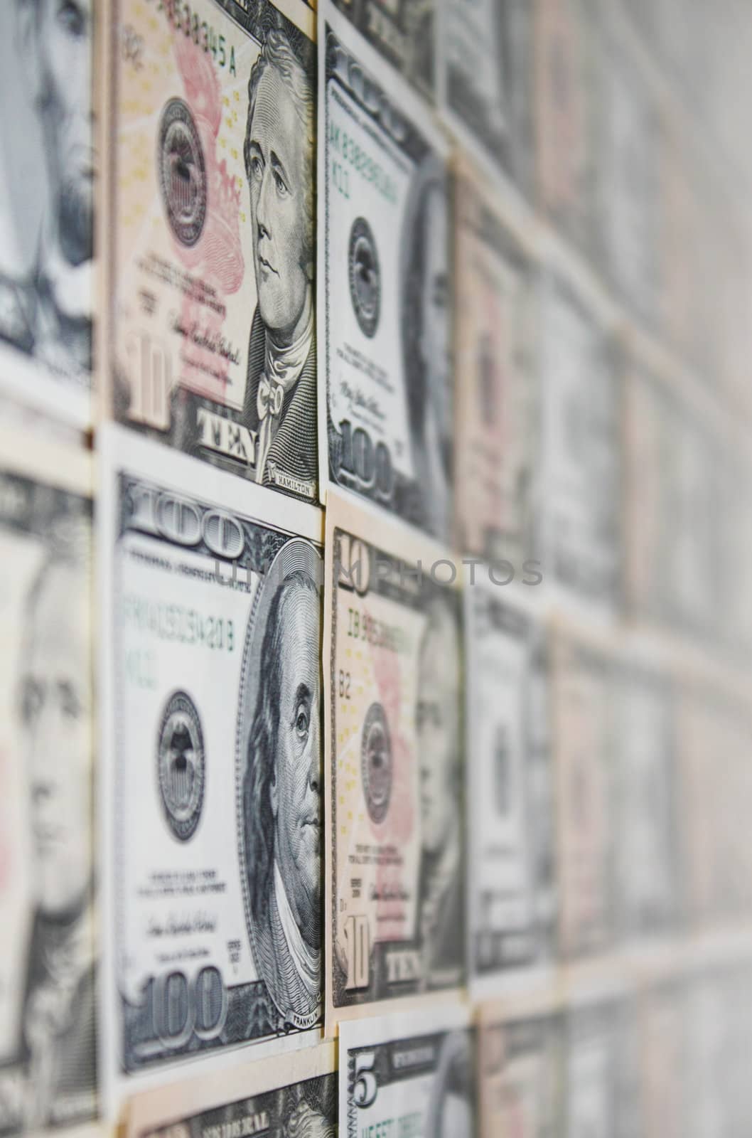 Background of ten and a hundred dollar banknotes on a wall, with shallow depth of field.