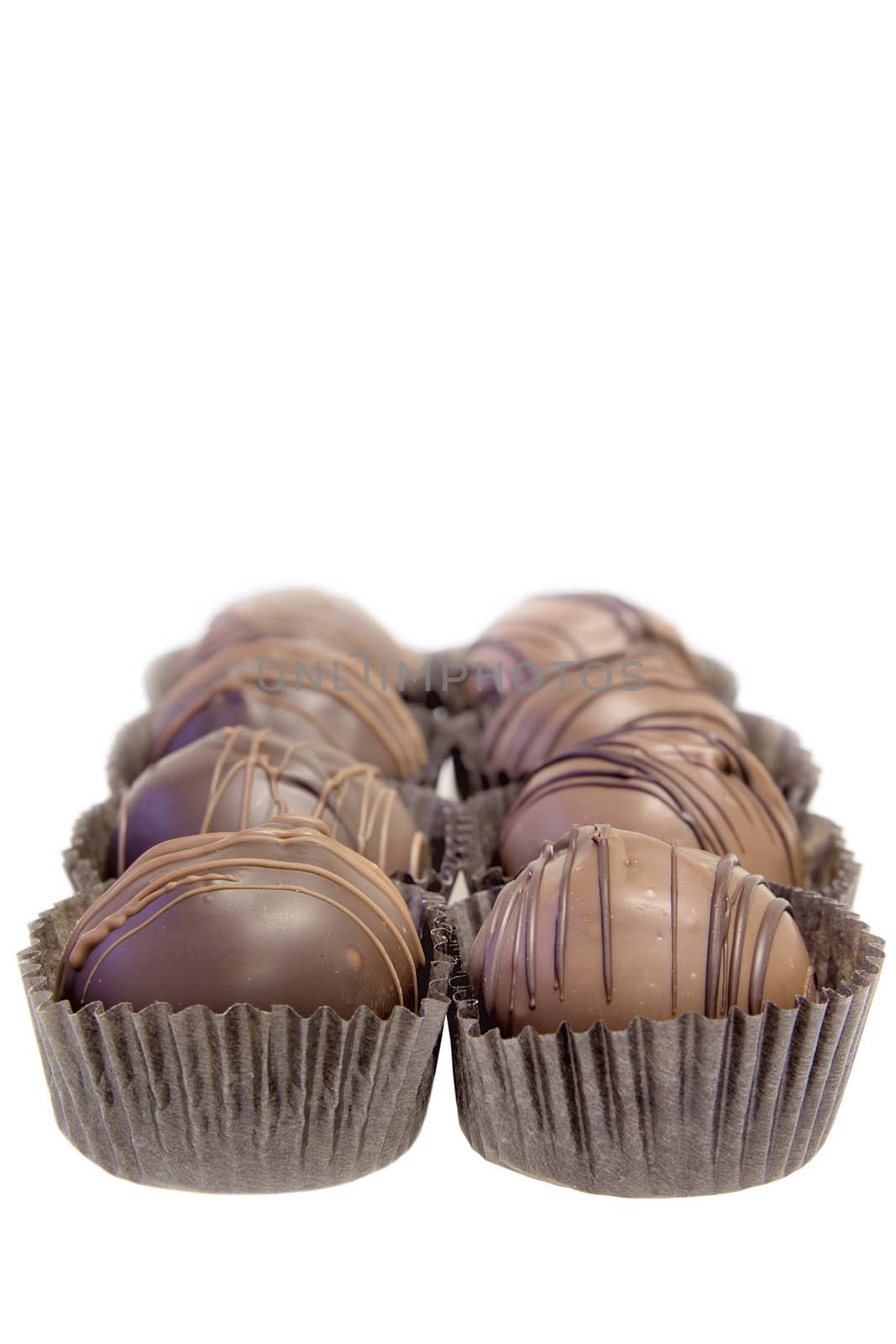 Two Rows of Dark and Milk Chocolate Truffles with Paper Base Liner Holders Isolated on White Background