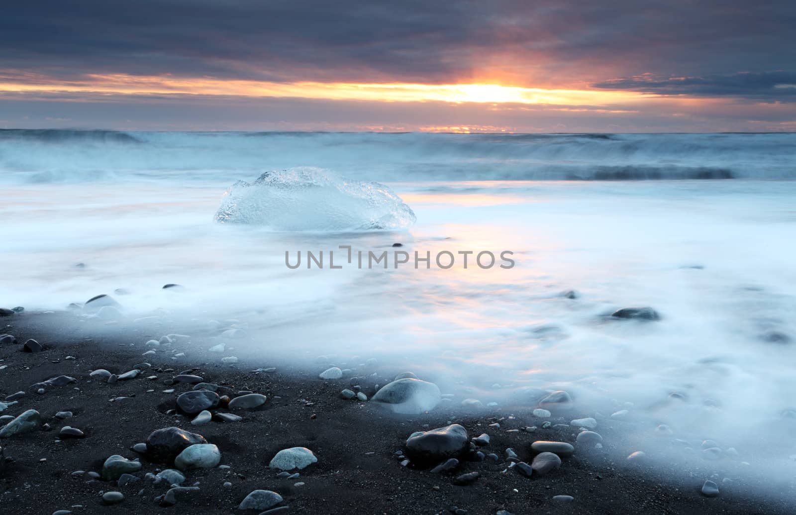 Ice on vocanic black sand iceland beach at sunset