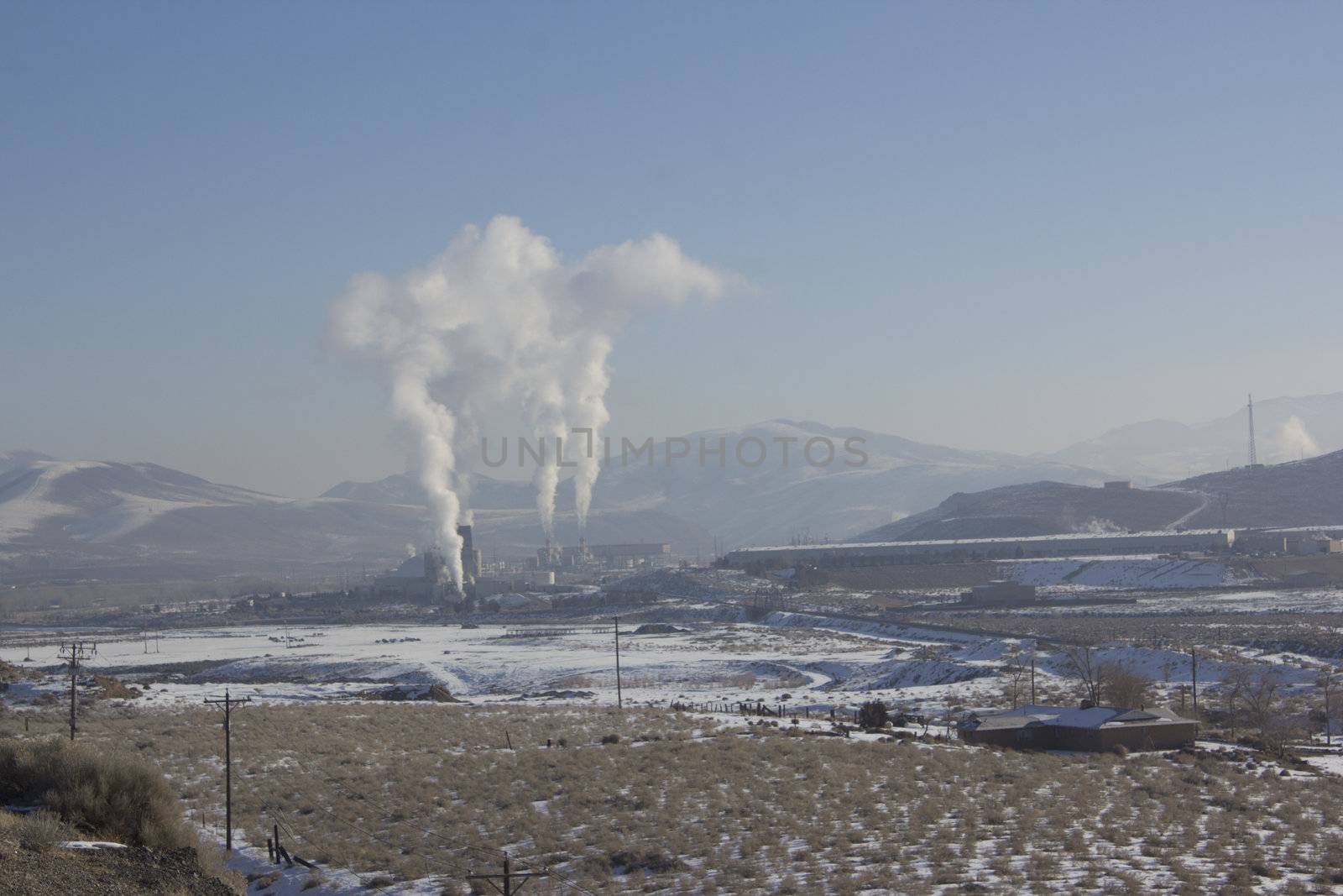 Power Plant smokestacks with blue skies and mountains