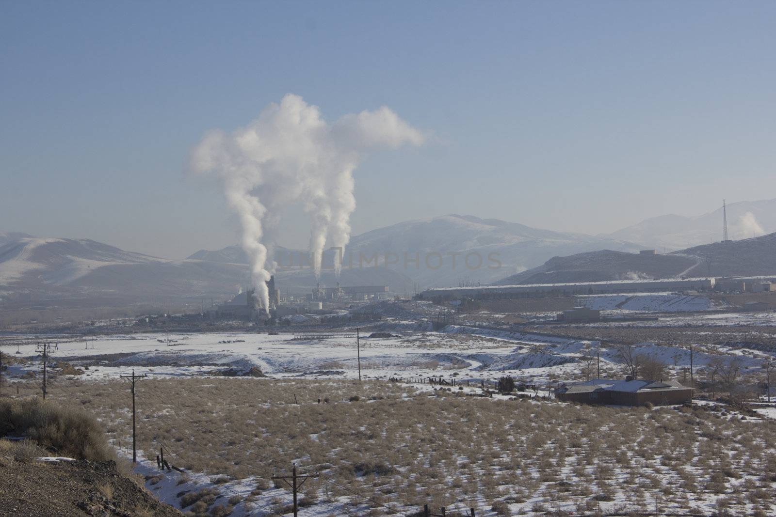 Power Plant smokestacks with blue skies and mountains