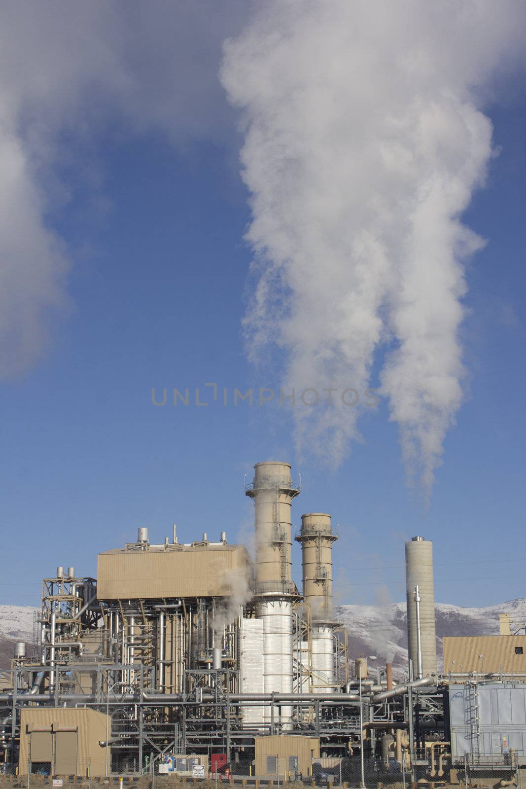 Power Plant smokestacks with blue skies and mountains