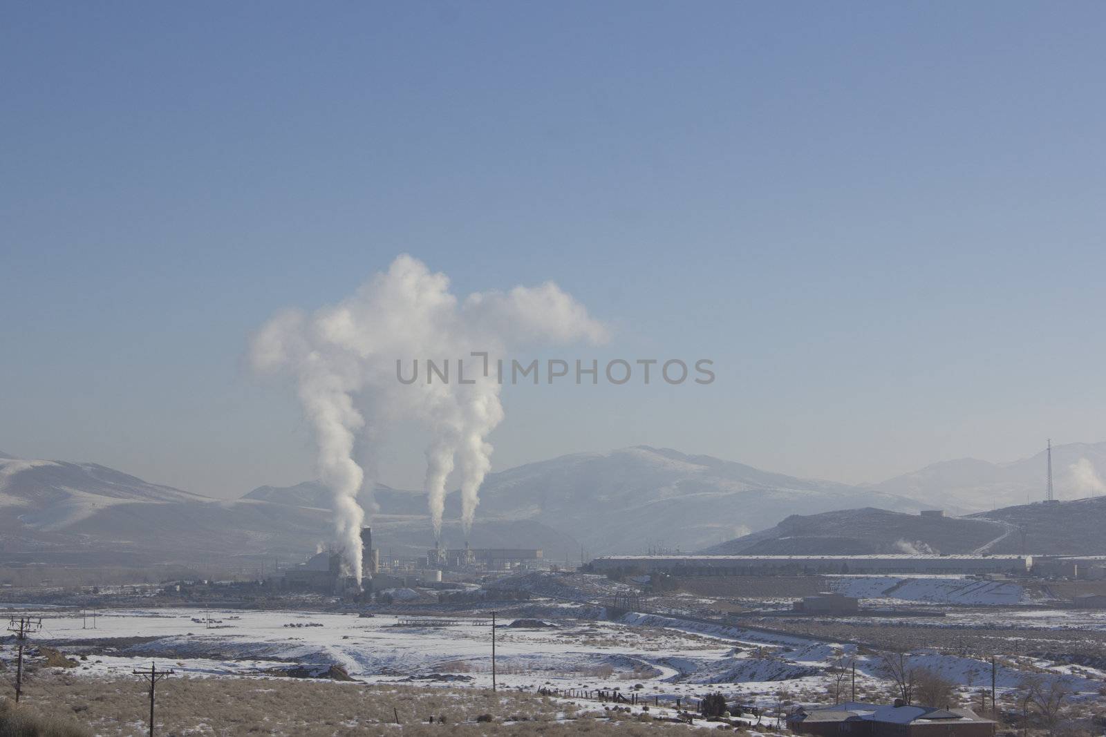 Power Plant smokestacks with blue skies and mountains