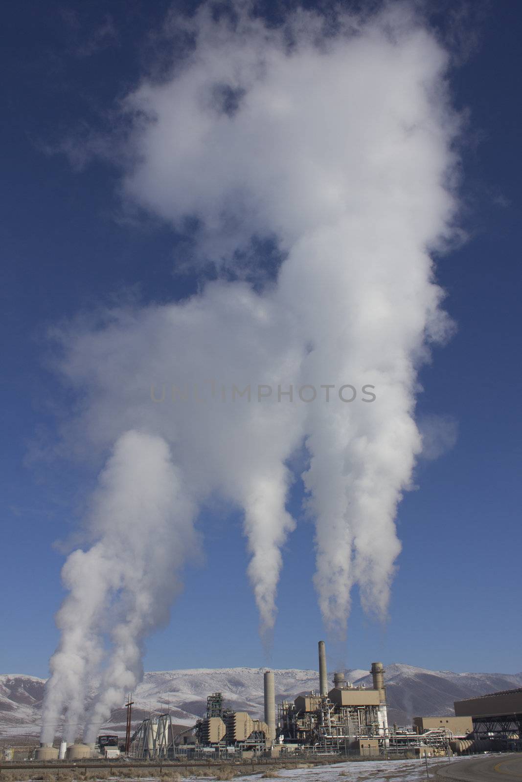 Power Plant smokestacks with blue skies and mountains