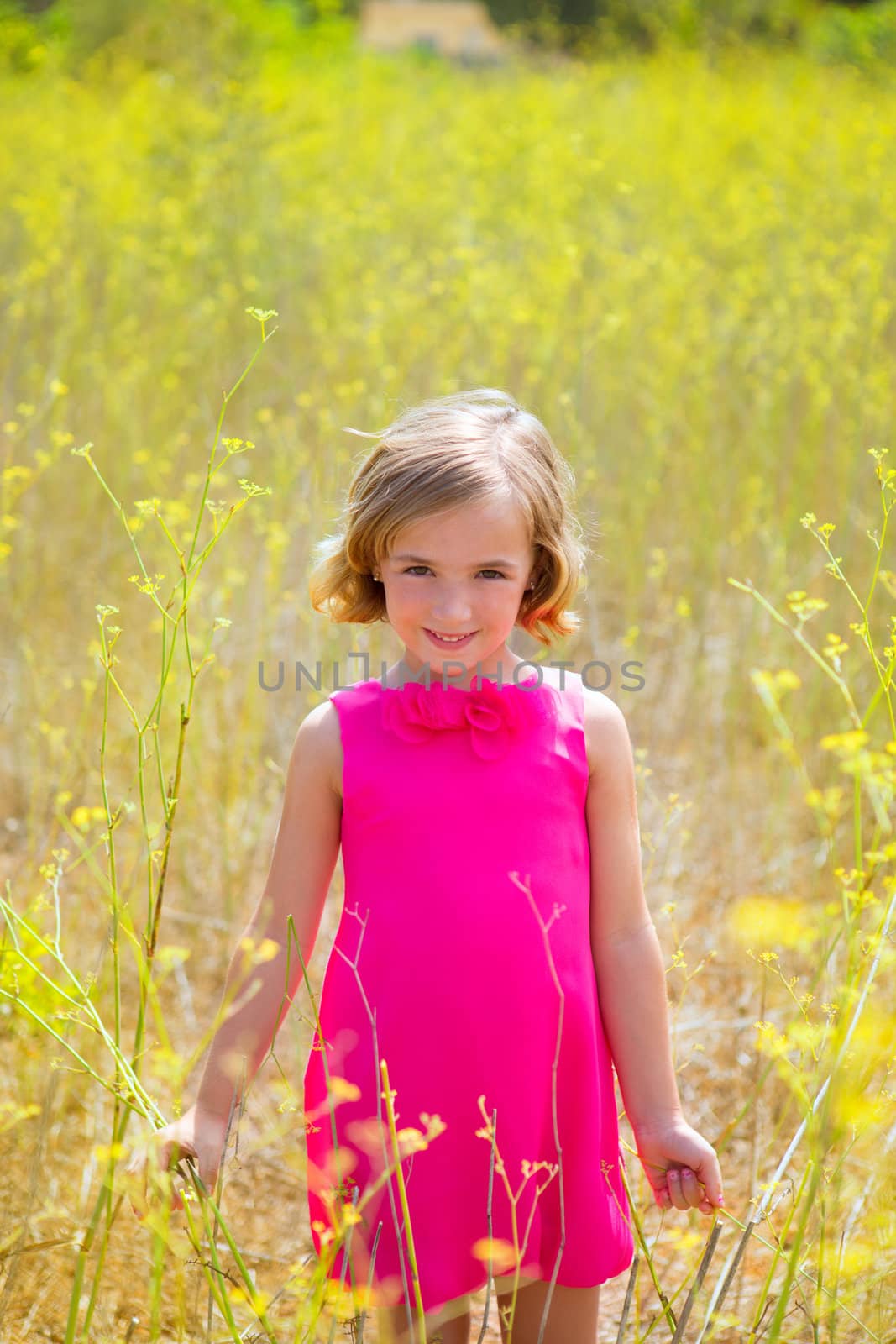 child kid girl in spring yellow flowers field and pink dress by lunamarina