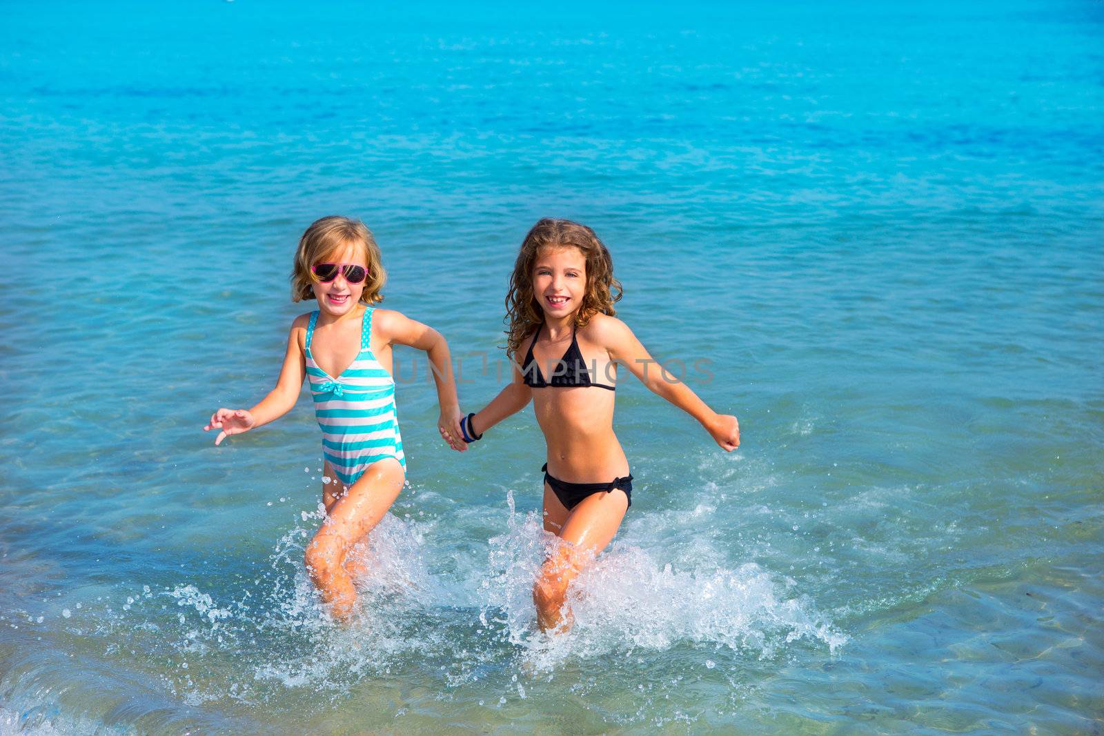 children girls friends running together in the beach shore on summer vacation
