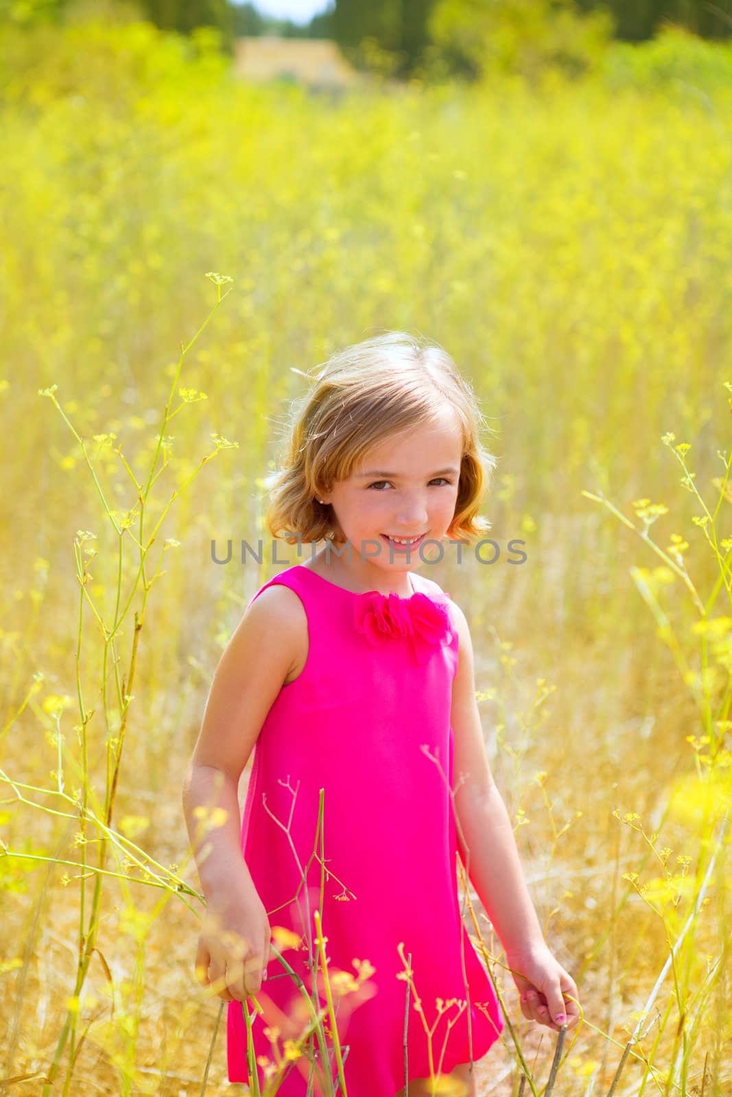 child kid girl in spring yellow flowers field and pink dress by lunamarina