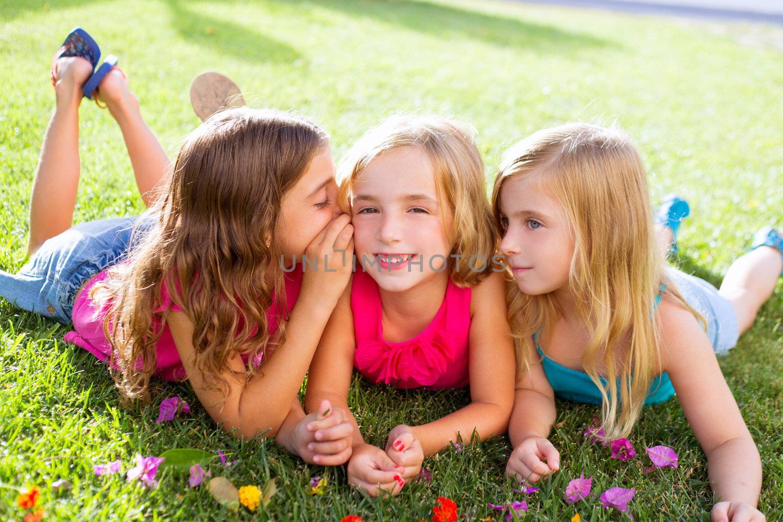 children girls playing whispering on flowers grass by lunamarina