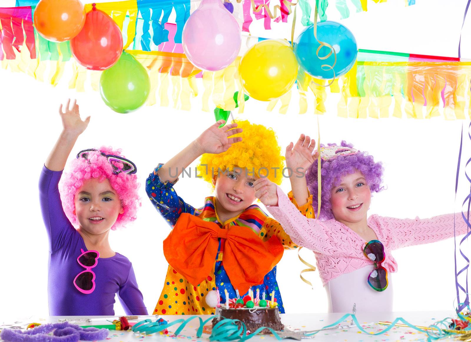 Children happy birthday party with clown wigs and chocolate cake