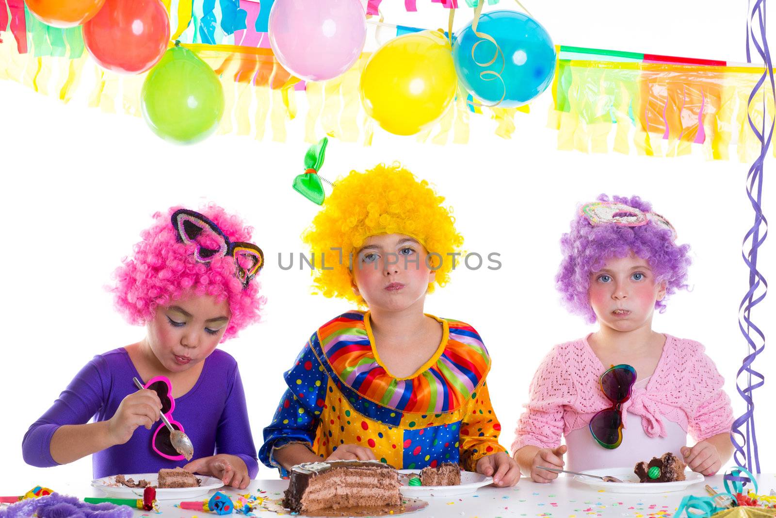 Children happy birthday party eating chocolate cake with clown wigs