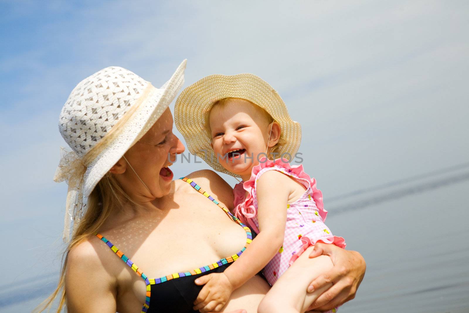 portrait of laughing mother and daugther on the seashore. Focus on the child