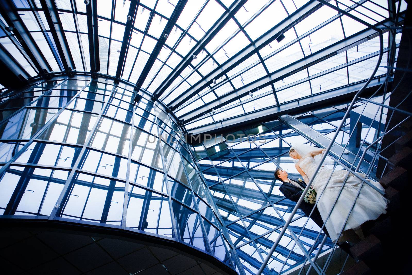 bride and groom under the glass ceiling