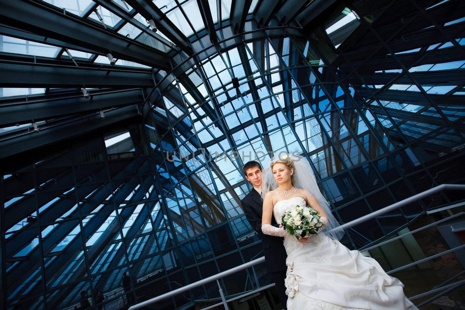 bride and groom under the glass ceiling