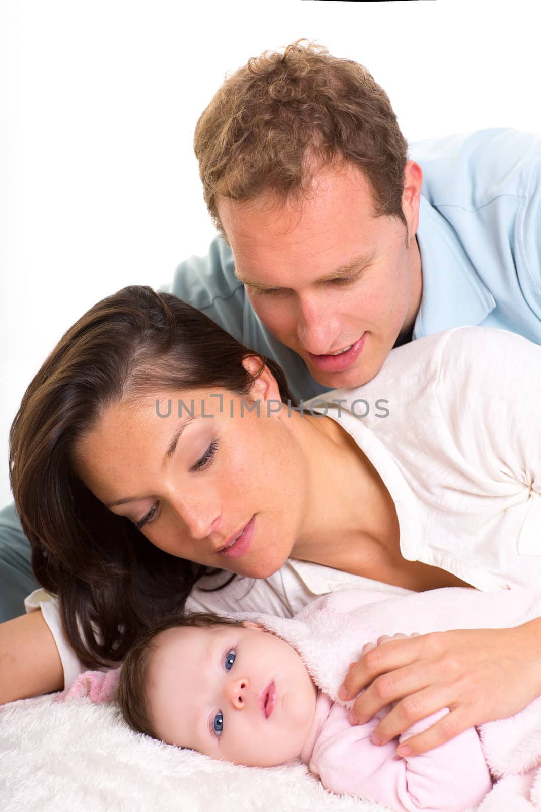 Baby girl mother and father family happy lying together on white fur