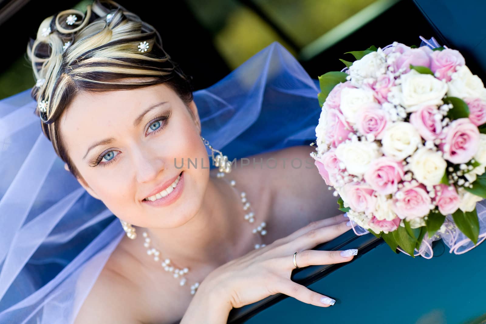 happy bride with flower bouquet siting in the car