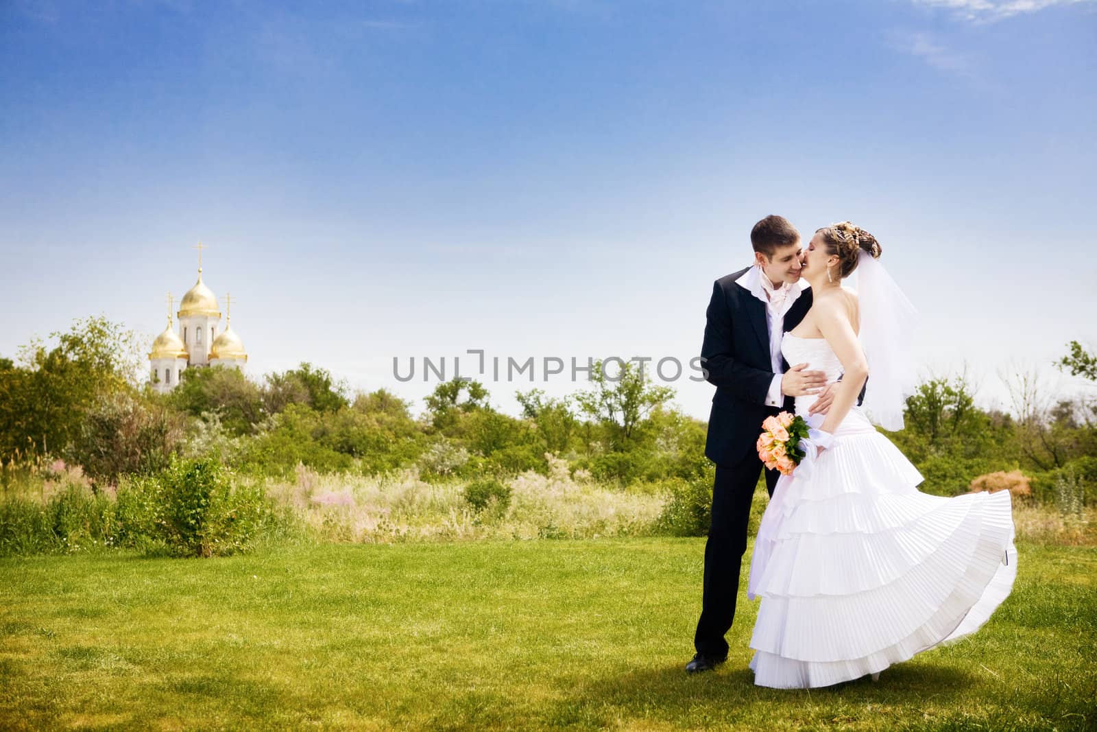 groom kisses bride near the church