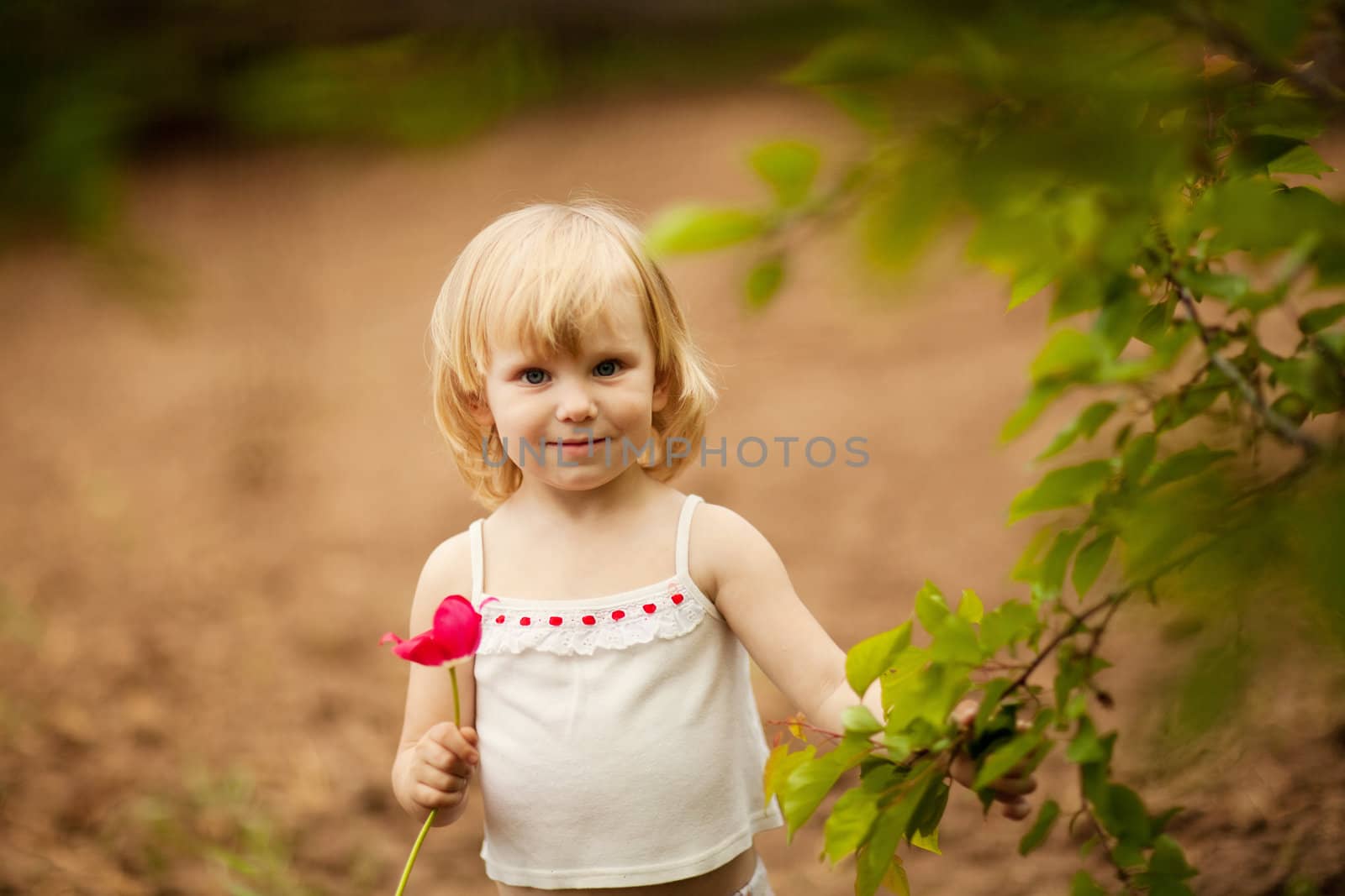 happy small girl with tulip outdoors in sunny day