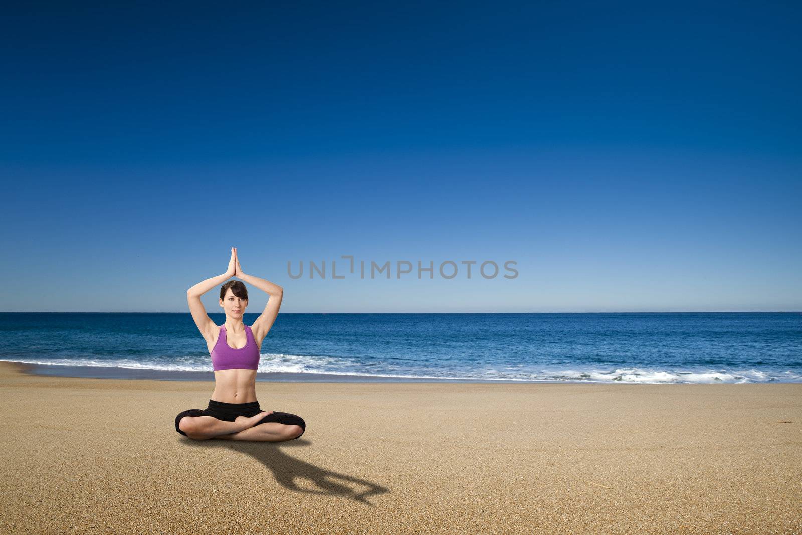 Beautiful athletic young woman doing Yoga exercises in the beach