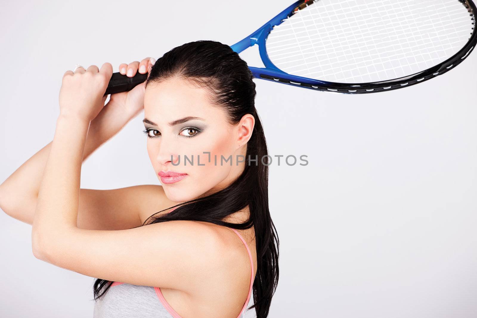 Female tennis player holding racket behind head