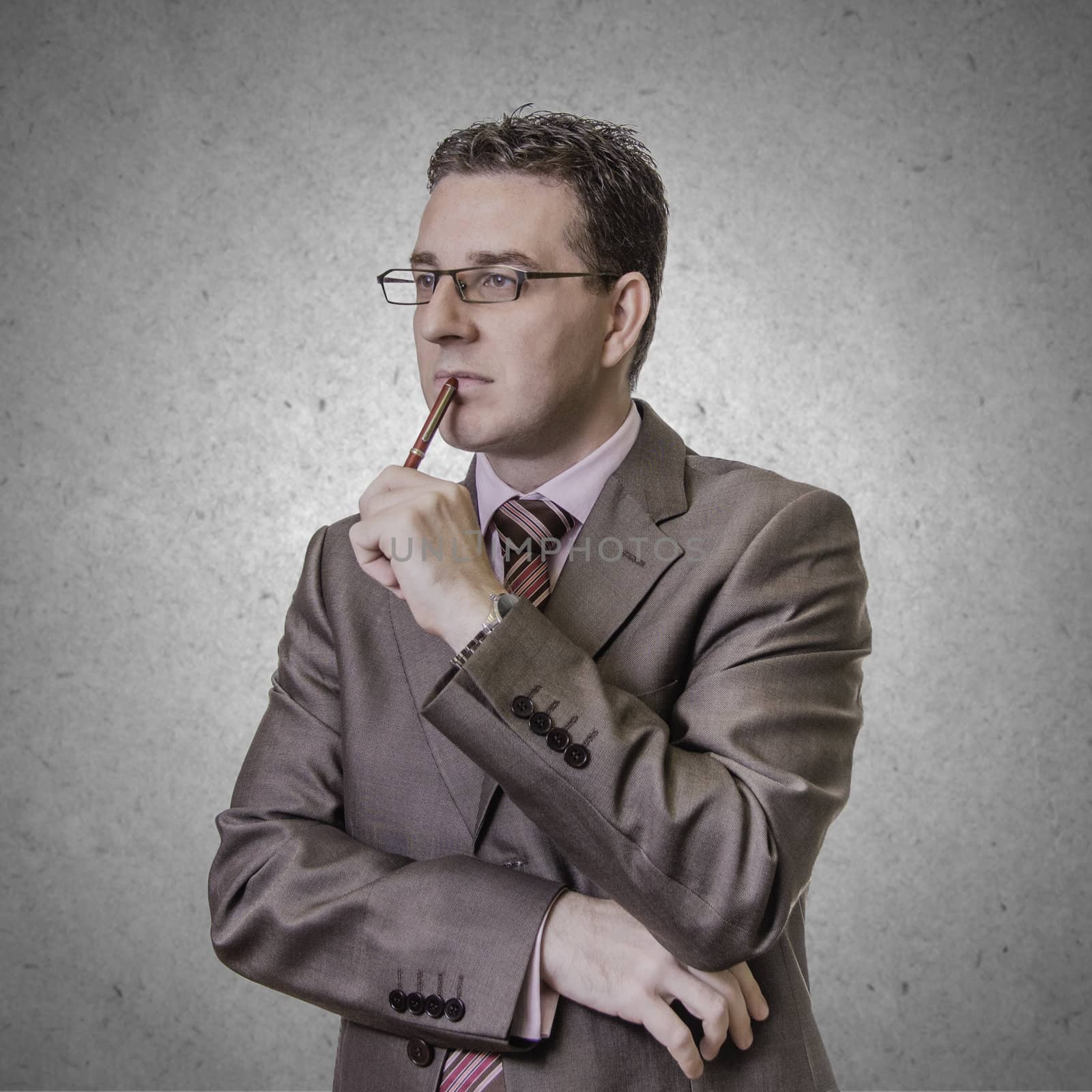 Portrait of thoughtful young businessman wlth pen in his hand, isolated on white background