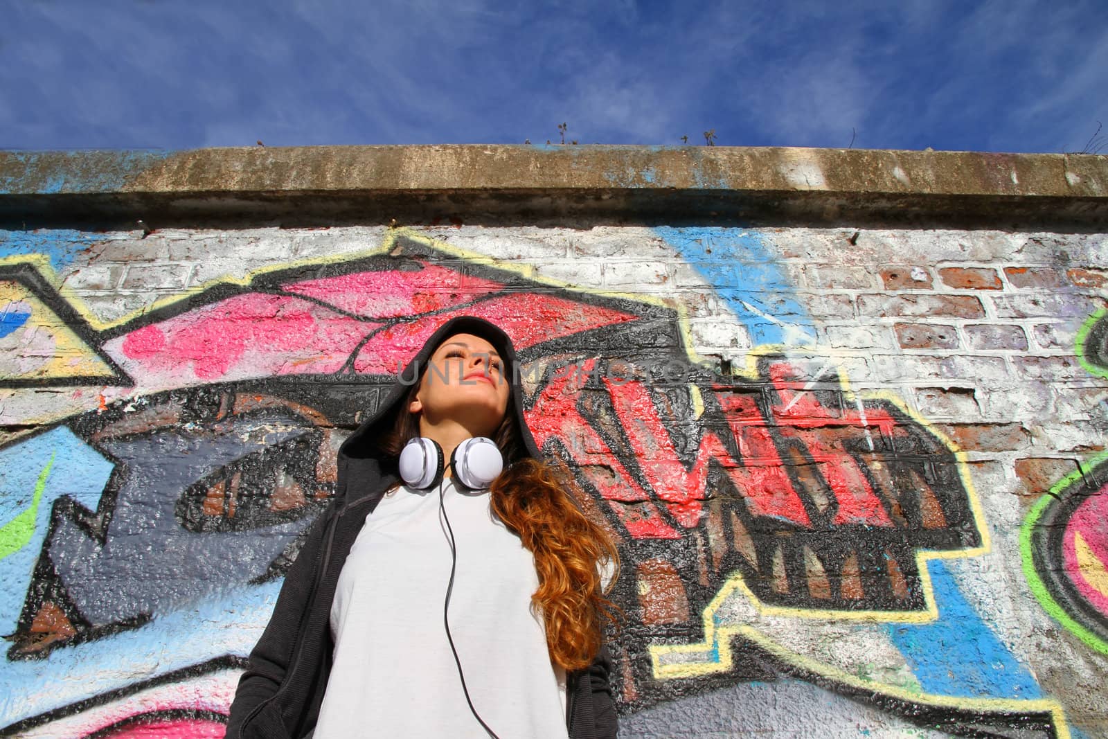 A young woman enjoying the Sunlight leaning against a wall.