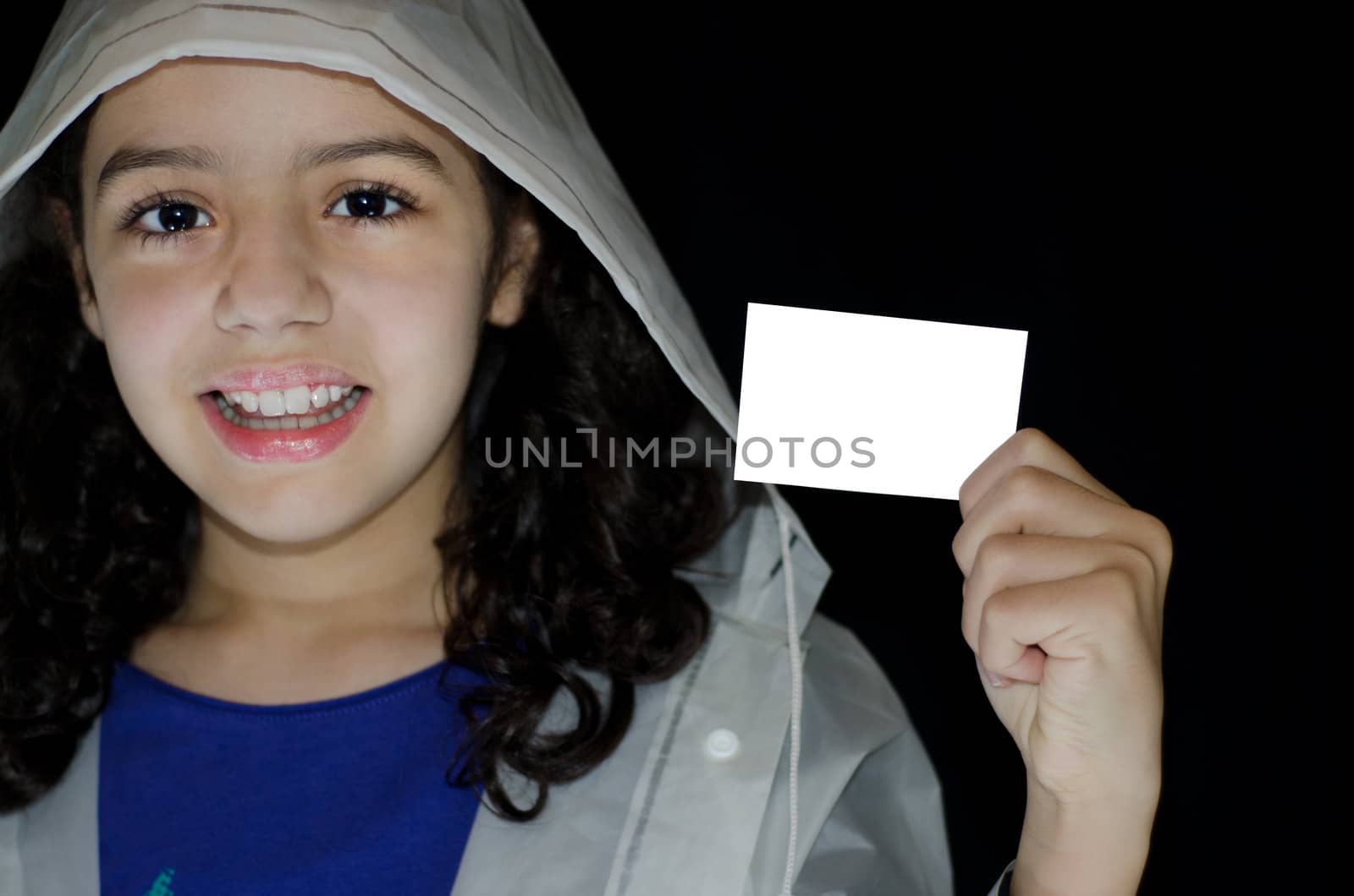 Child in raincoat holding a white greeting card on a black background.