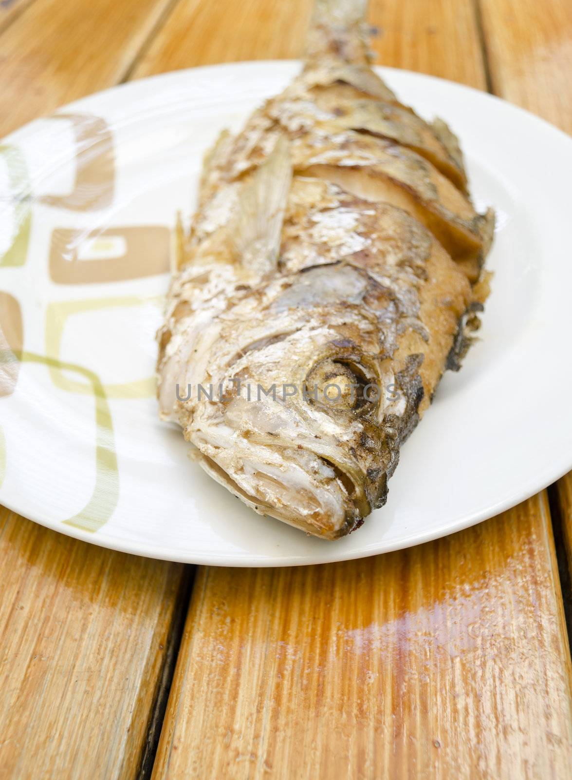 Fried fish on white dish by siraanamwong